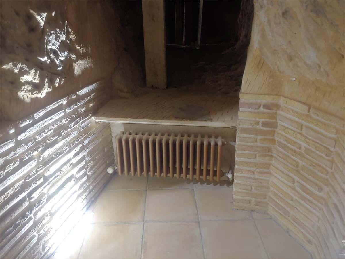 Una habitación con una pared de ladrillos y un radiador en el suelo.