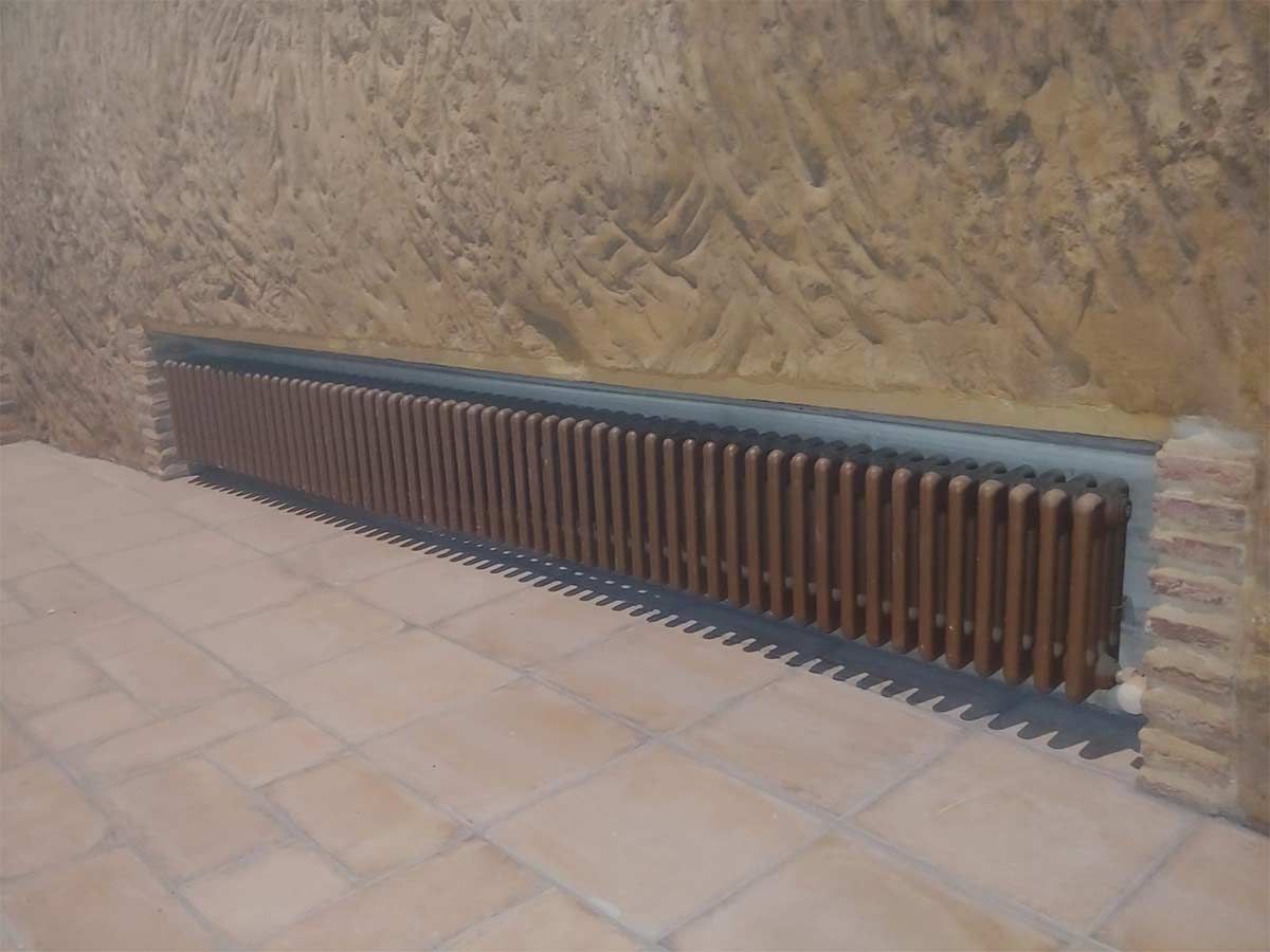 Un radiador de madera está colocado sobre un suelo de baldosas al lado de una pared.