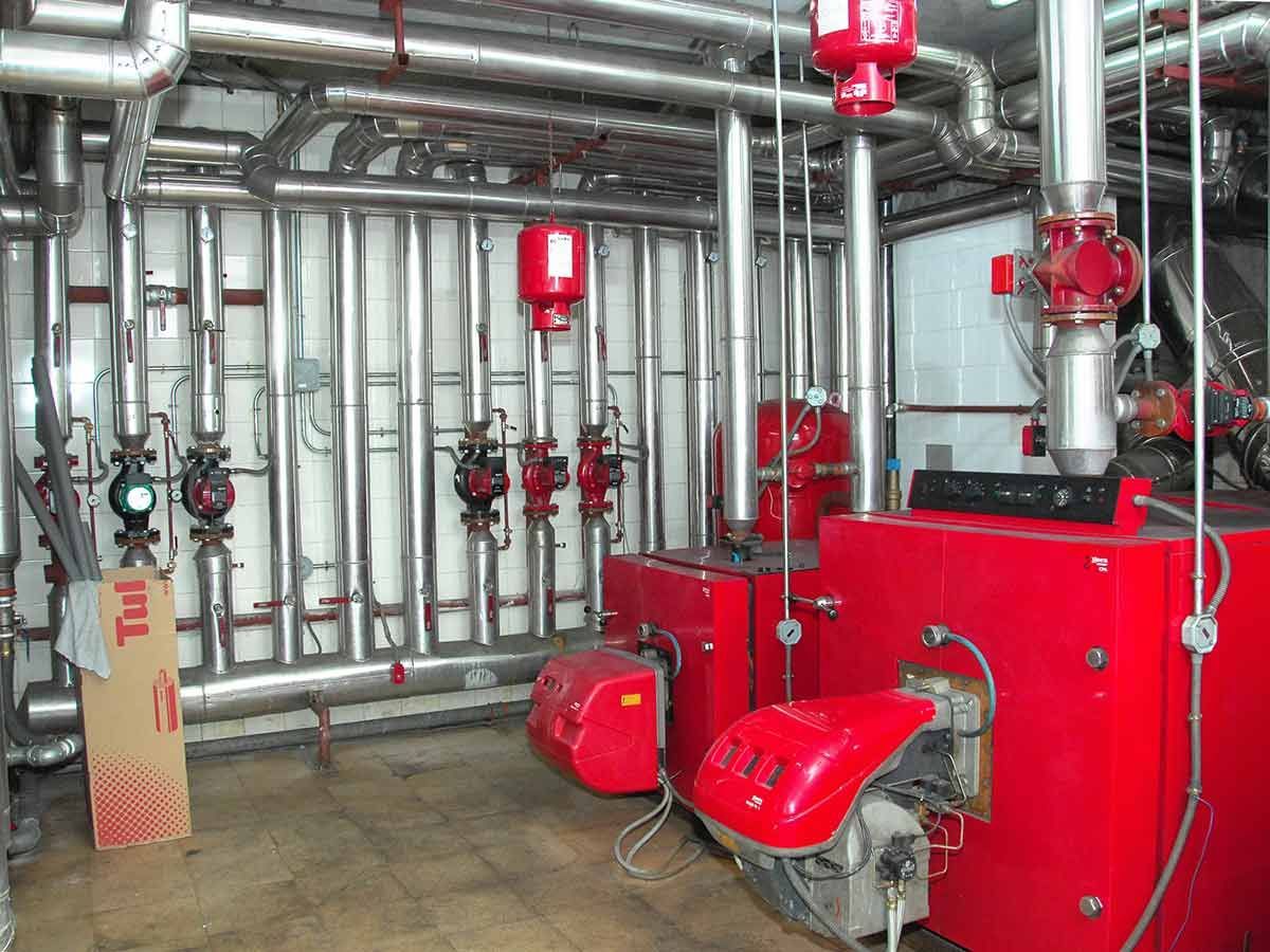 Una habitación con muchas tuberías y una caldera roja.