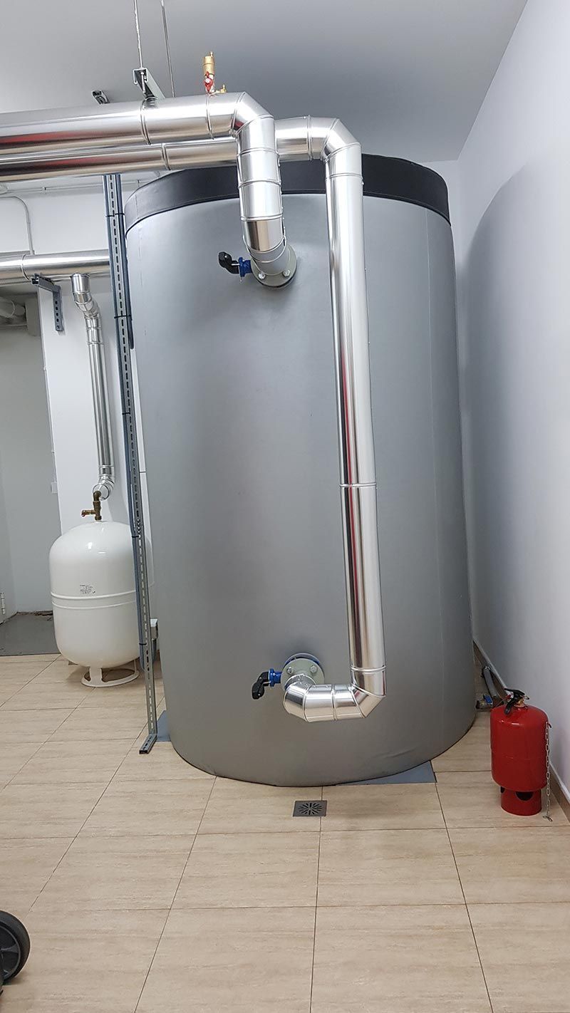 Un gran tanque gris se encuentra en una habitación al lado de un extintor de incendios.