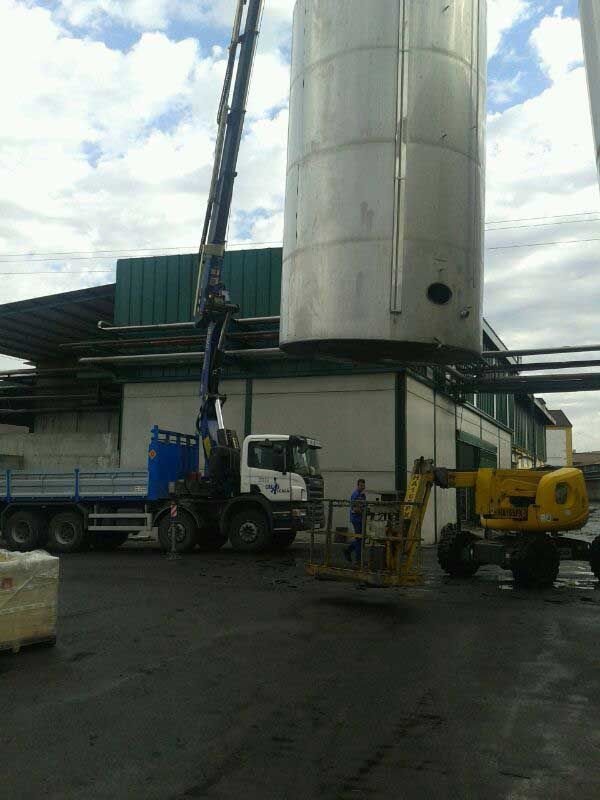 Un camión está siendo levantado por una grúa frente a un edificio.