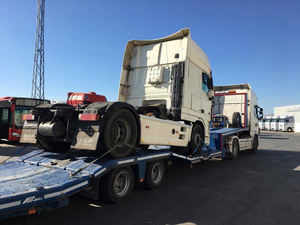 Un camión semirremolque está siendo remolcado por un remolque de plataforma.