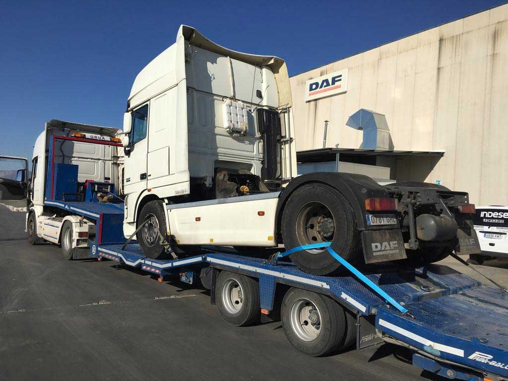 Un camión semirremolque está siendo remolcado por un remolque de plataforma.