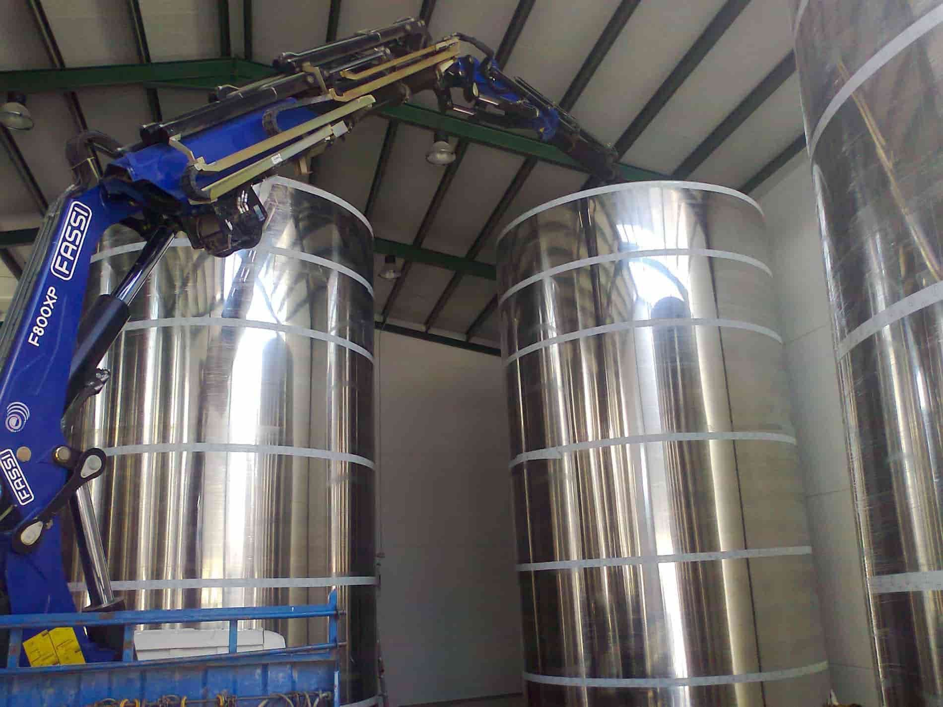 Un gran tanque de acero inoxidable está siendo levantado por una grúa.