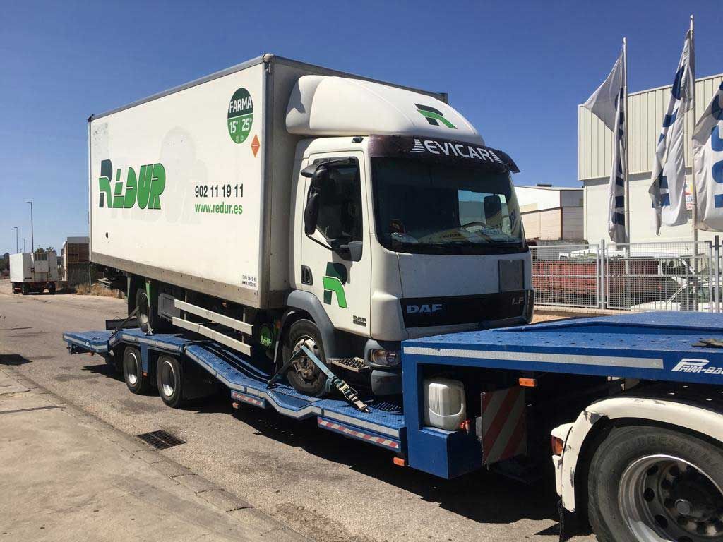 Un camión blanco con un logo verde en el costado está estacionado en un estacionamiento.