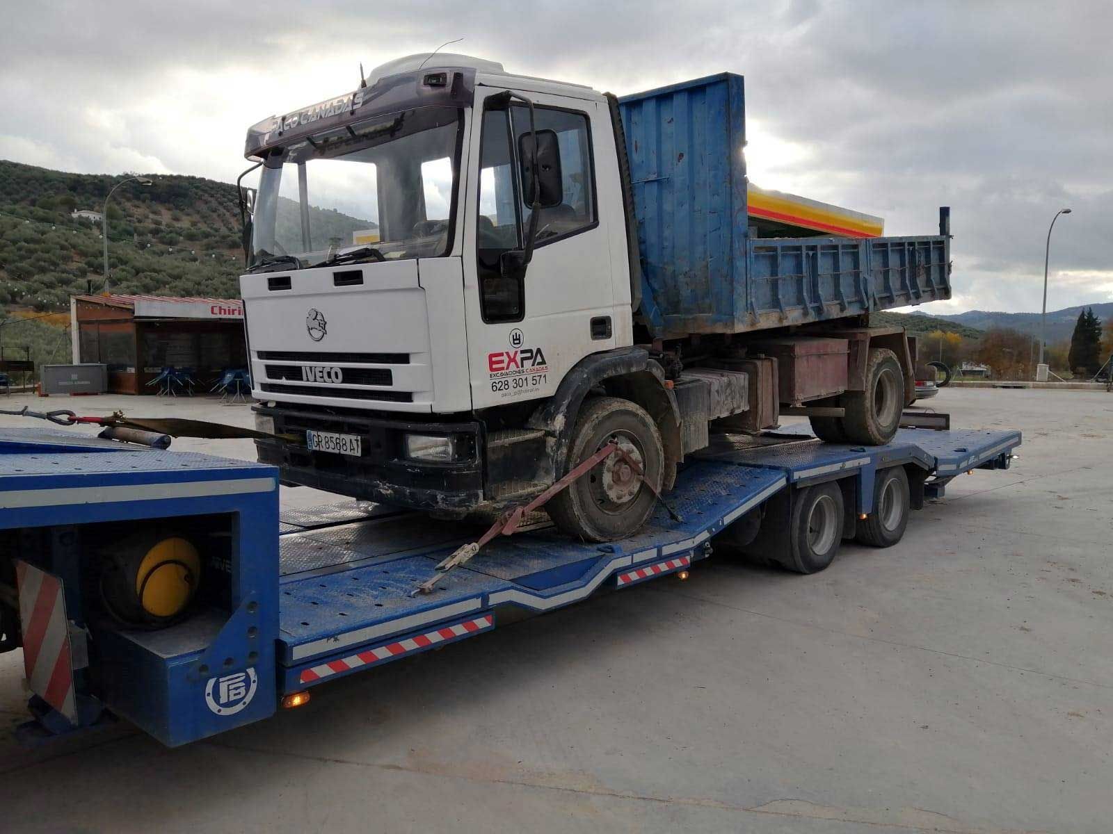 Un camión blanco está sentado encima de un remolque azul.