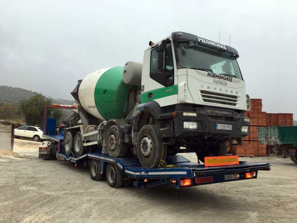 Un camión hormigonera está siendo remolcado por un remolque.