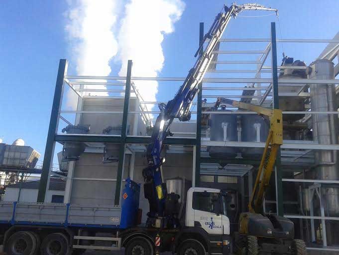 Un camión con una grúa encima está estacionado frente a un edificio.
