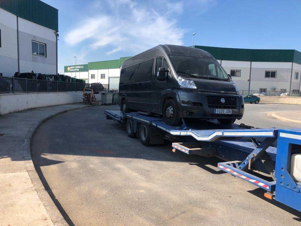 Una camioneta negra está sentada encima de un remolque.