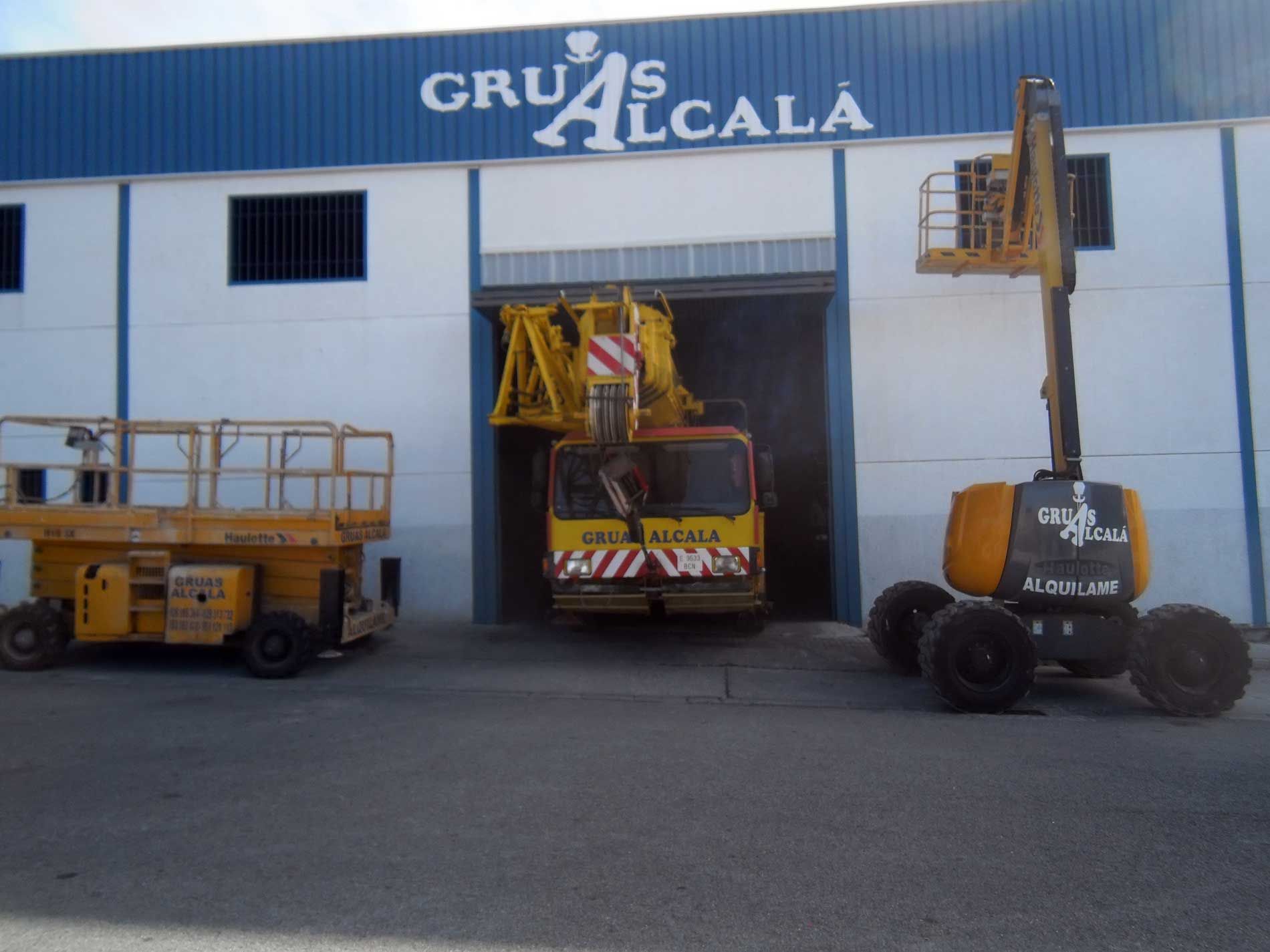 Dos vehículos están estacionados frente a un edificio que dice gruas alcala