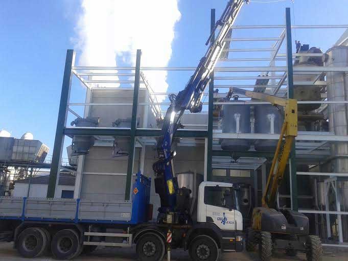 Un camión con una grúa acoplada está estacionado delante de un edificio.