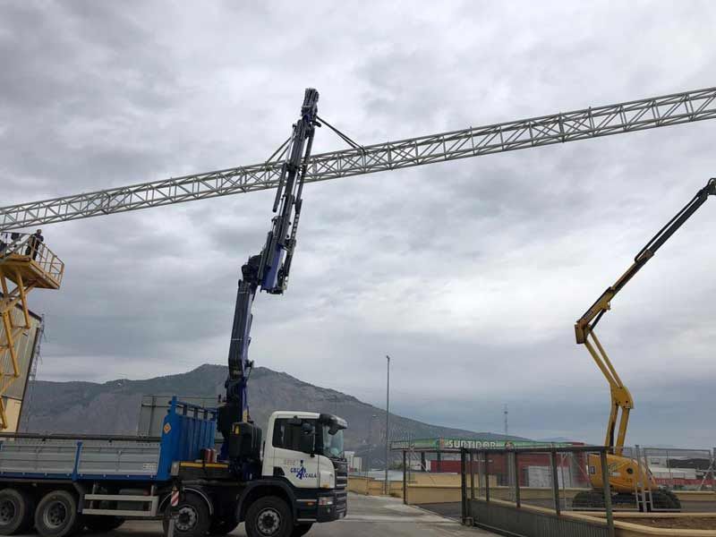 Un camión con una grúa acoplada está aparcado delante de una obra en construcción.