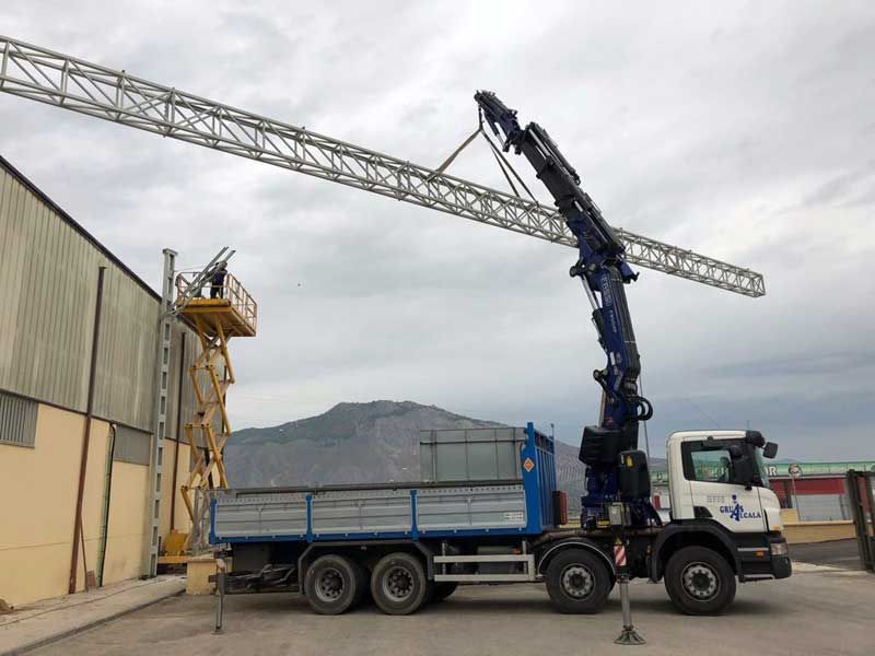 Un camión con una grúa acoplada está estacionado delante de un edificio.