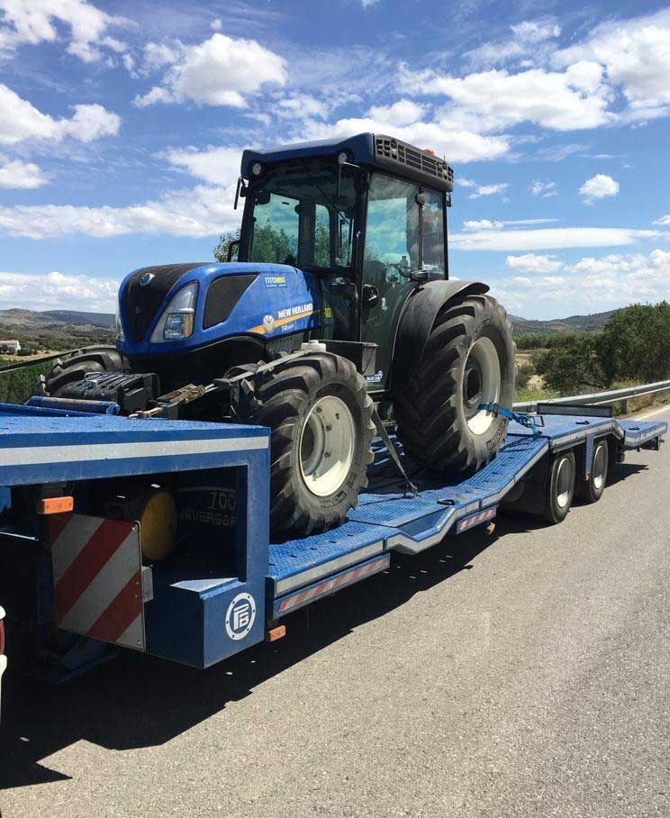Un tractor azul está sentado encima de un remolque azul.
