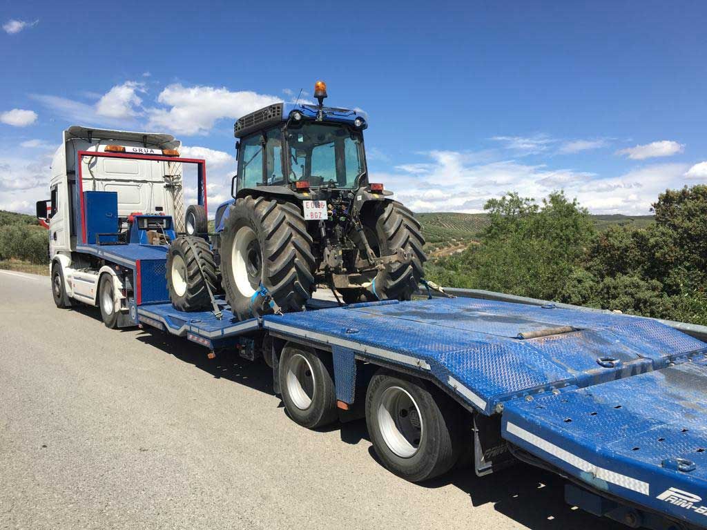 Un tractor está siendo remolcado por un camión de plataforma.