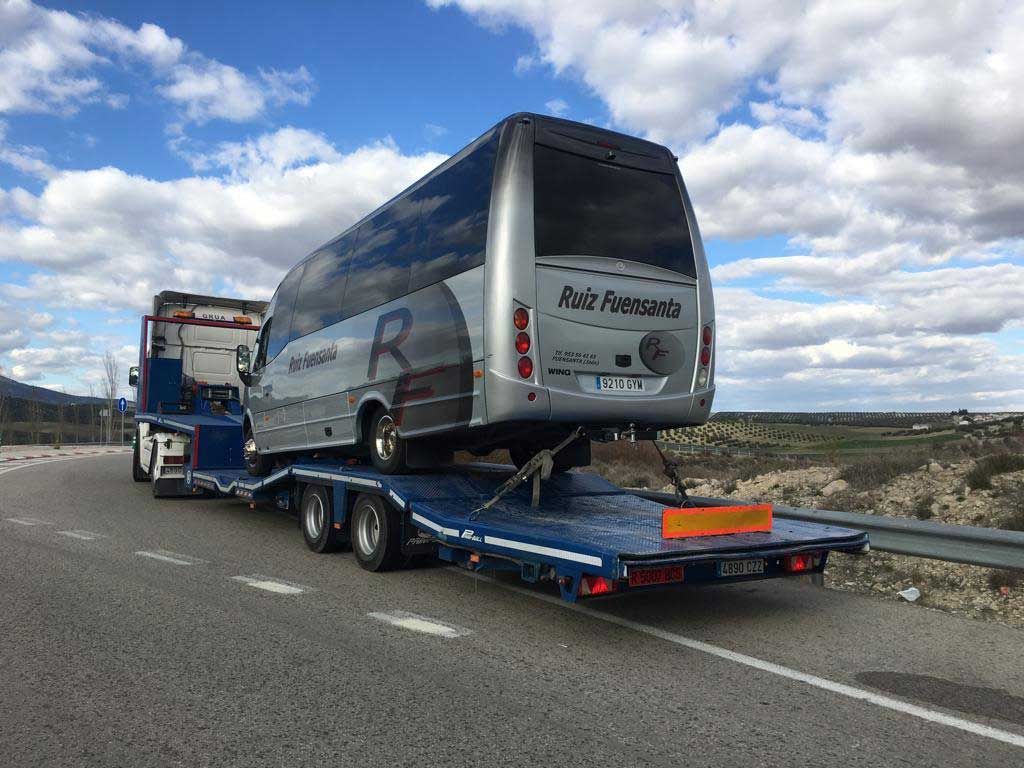 Un autobús está siendo remolcado por una autopista por una grúa.