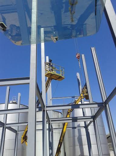 Un hombre está parado sobre una grúa frente a un edificio en construcción.
