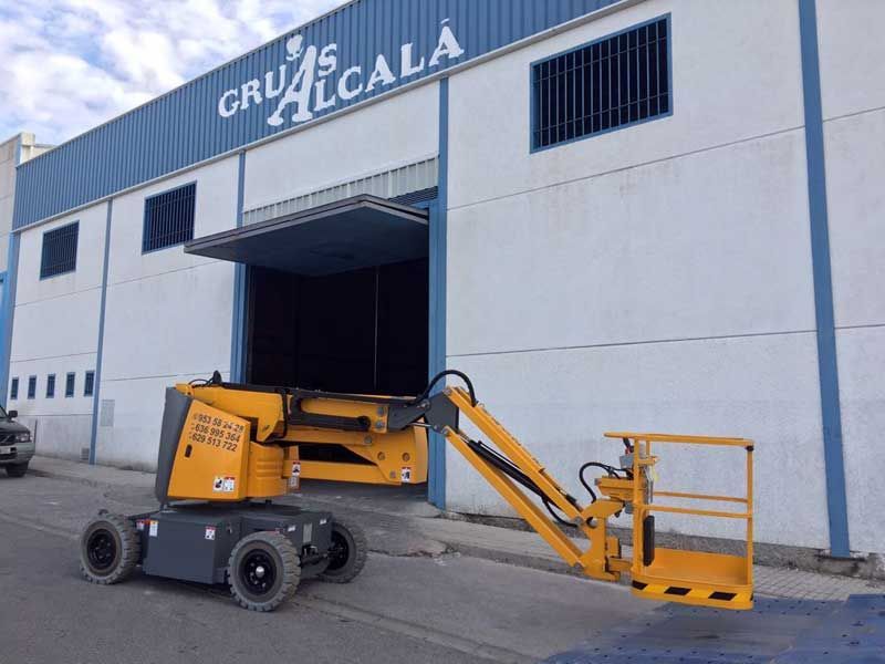 Un ascensor amarillo está estacionado frente a un edificio que dice gru alcala