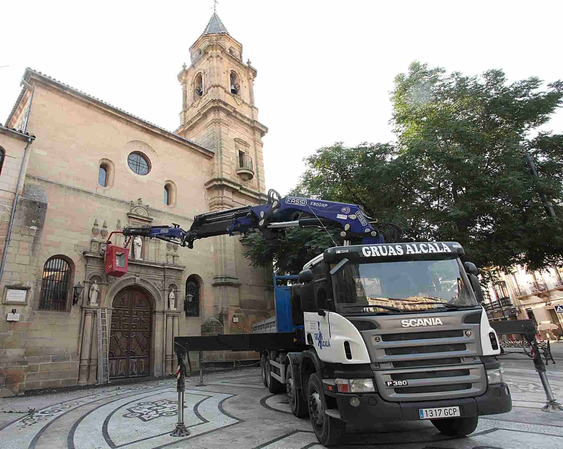 Un camión con una grúa en la parte trasera está estacionado frente a una iglesia.