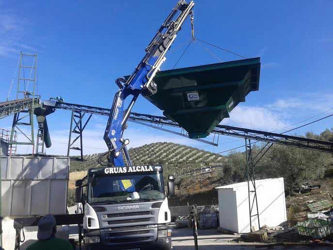 Una grúa está levantando un gran objeto verde sobre un camión.