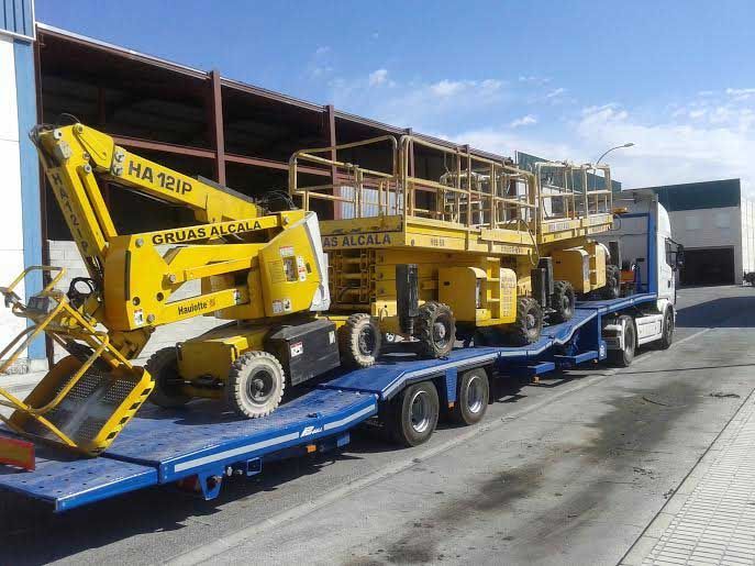 Una grúa amarilla está sentada encima de un remolque azul.