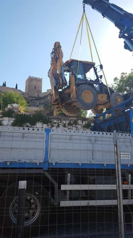 Un tractor está siendo levantado por una grúa encima de un camión.