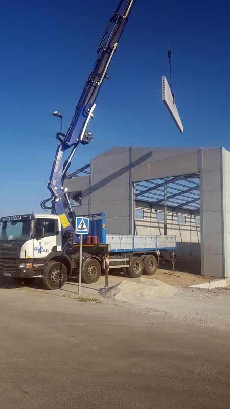 Una grúa está levantando un trozo de hormigón delante de un edificio.