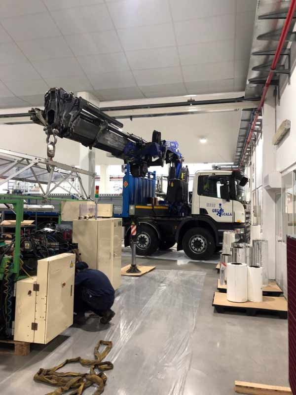 Se utiliza una grúa para levantar un camión en una fábrica.