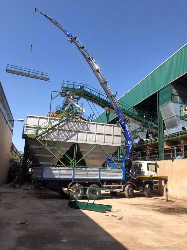 Un camión con una grúa acoplada está estacionado delante de un edificio.