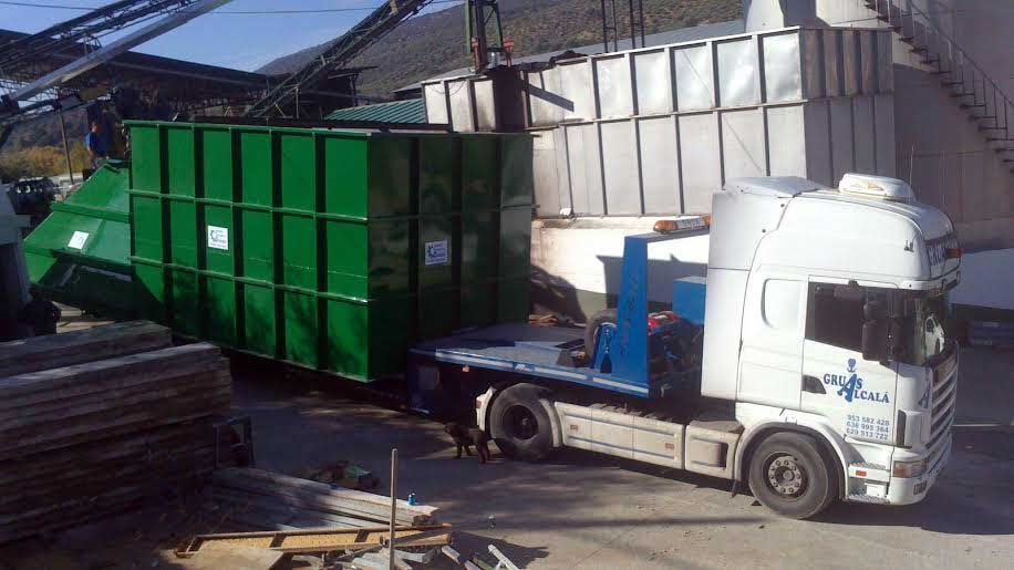 Un camión blanco con un contenedor verde en la parte trasera está estacionado en un estacionamiento.
