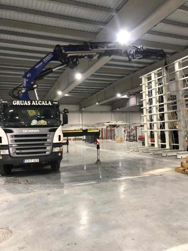 Un camión con una grúa encima está estacionado en un almacén.