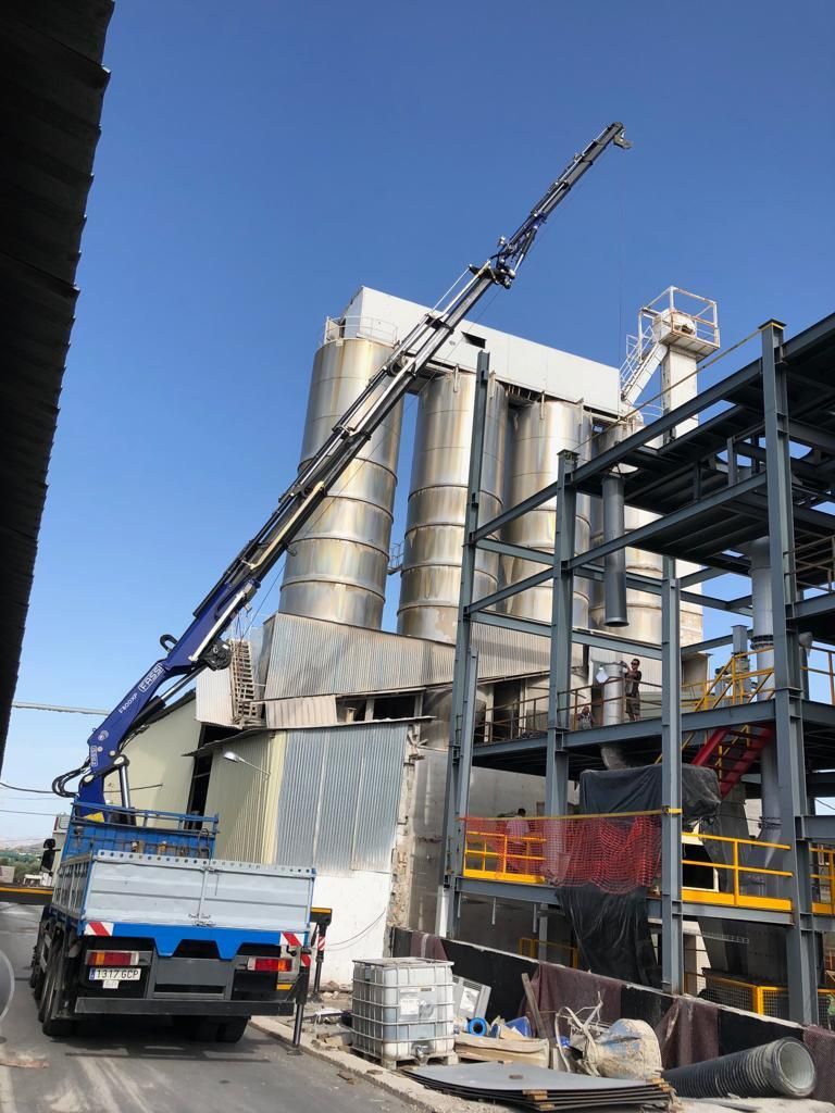 Un camión con una grúa acoplada está aparcado delante de un gran edificio.