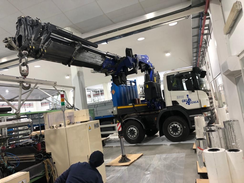 Se utiliza una grúa para levantar una máquina en una fábrica.