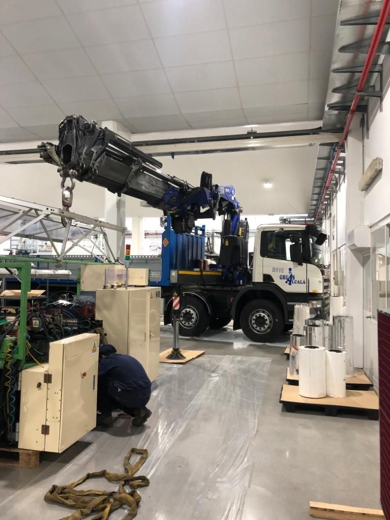 Un camión con una grúa encima está en una fábrica.
