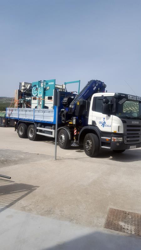 Un camión azul y blanco con una grúa en la parte trasera está estacionado en un estacionamiento.
