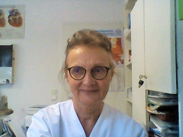 Medizinische Fachkraft mit Handschuhen hält kleinen Hund auf den Händen.