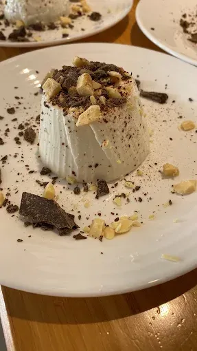 Un plato blanco coronado con un postre con virutas de chocolate y nueces.