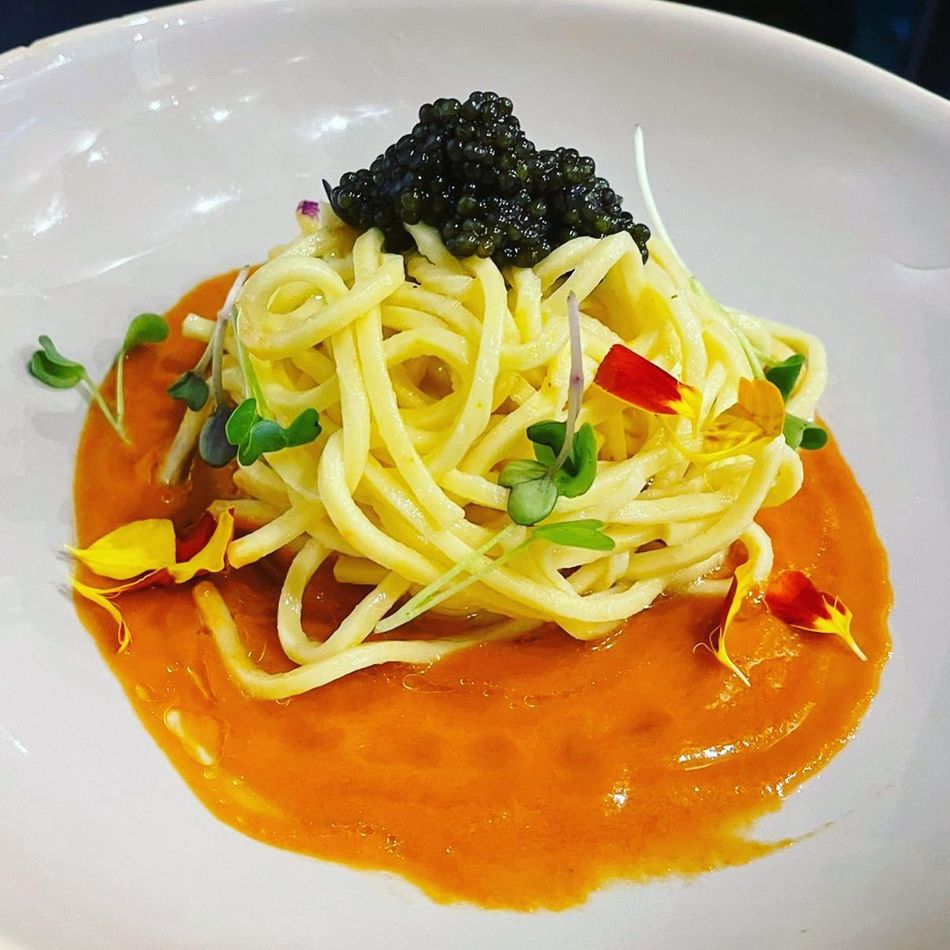 Un plato de espaguetis con salsa de tomate y caviar encima.