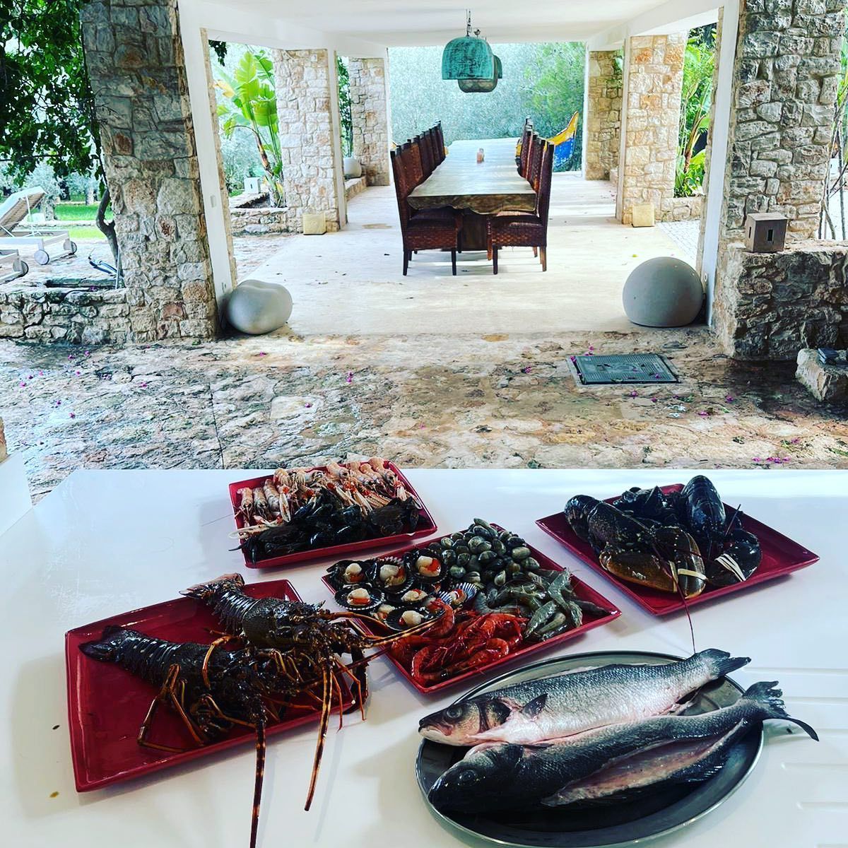 Una mesa con platos de mariscos, incluyendo langostas y pescado.