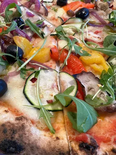 Un primer plano de una pizza con verduras y aceitunas encima.