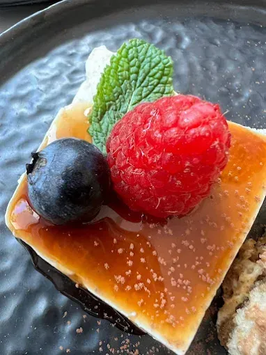 Un primer plano de un postre con frambuesas y arándanos en un plato.