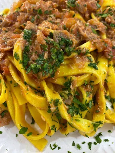 Un primer plano de un plato de pasta con carne y salsa.