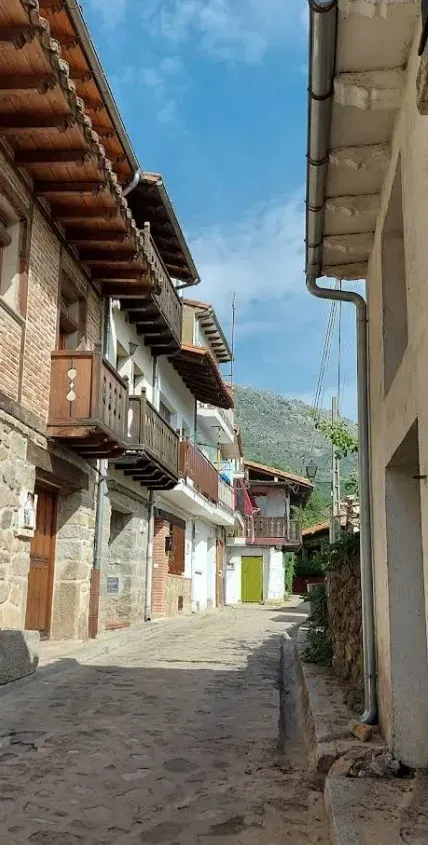 Una calle estrecha entre dos edificios con montañas al fondo.