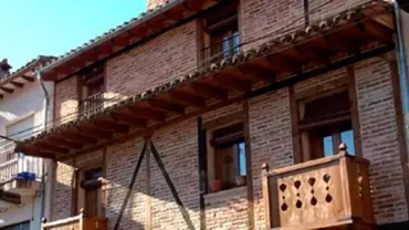 Un edificio de ladrillo con un balcón y una barandilla de madera.