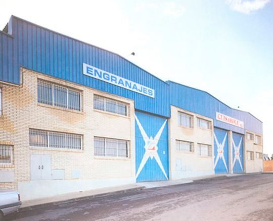 Edificio industrial azul con grandes puertas pintadas en forma de estrella y un letrero que dice “ENGRANAJES”.
