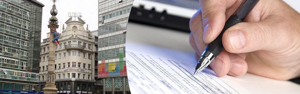 Edificio histórico junto a una mano que firma un documento, simbolizando la planificación urbana o trámites legales.