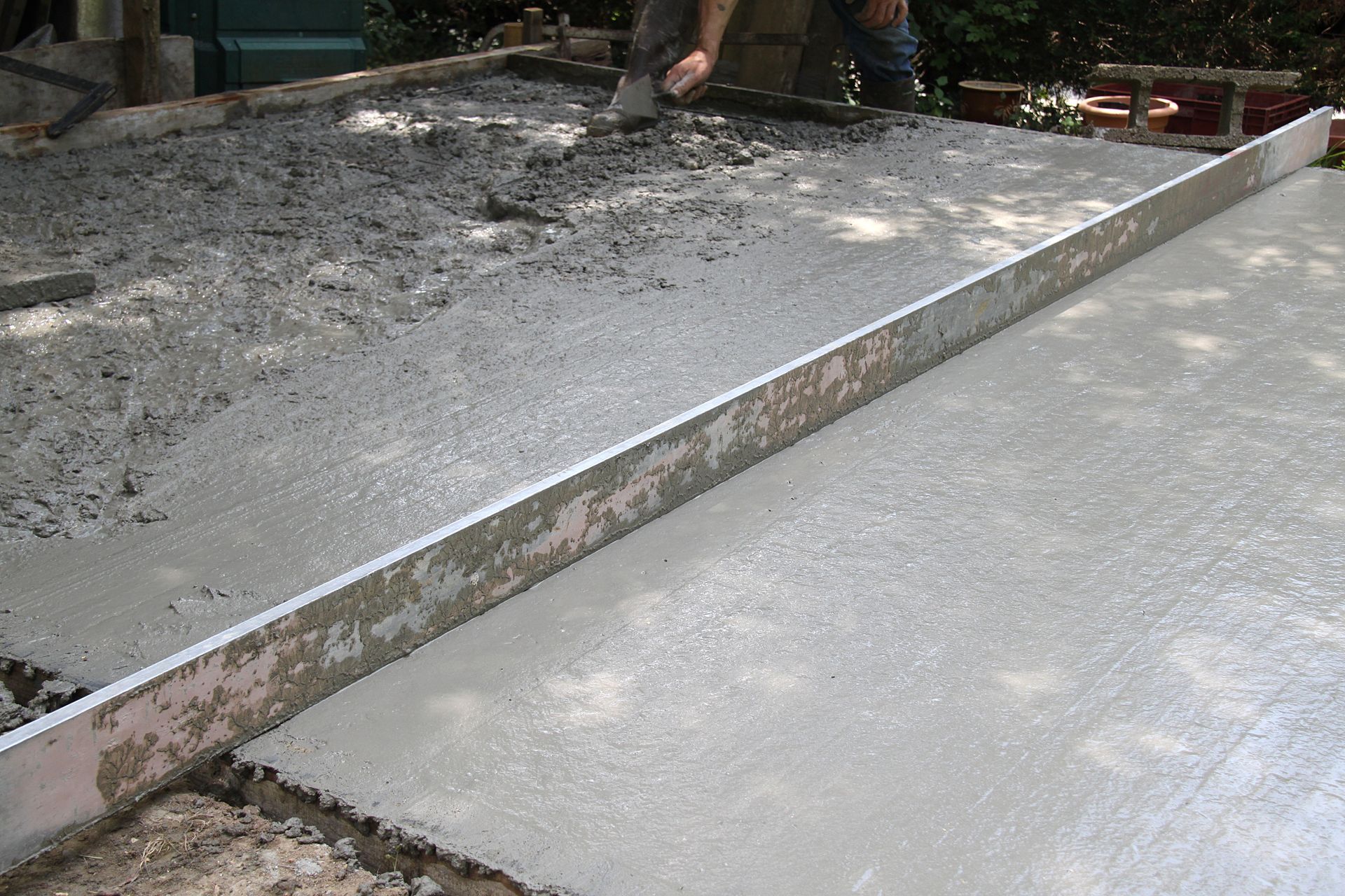 Du béton frais est nivelé à la règle.