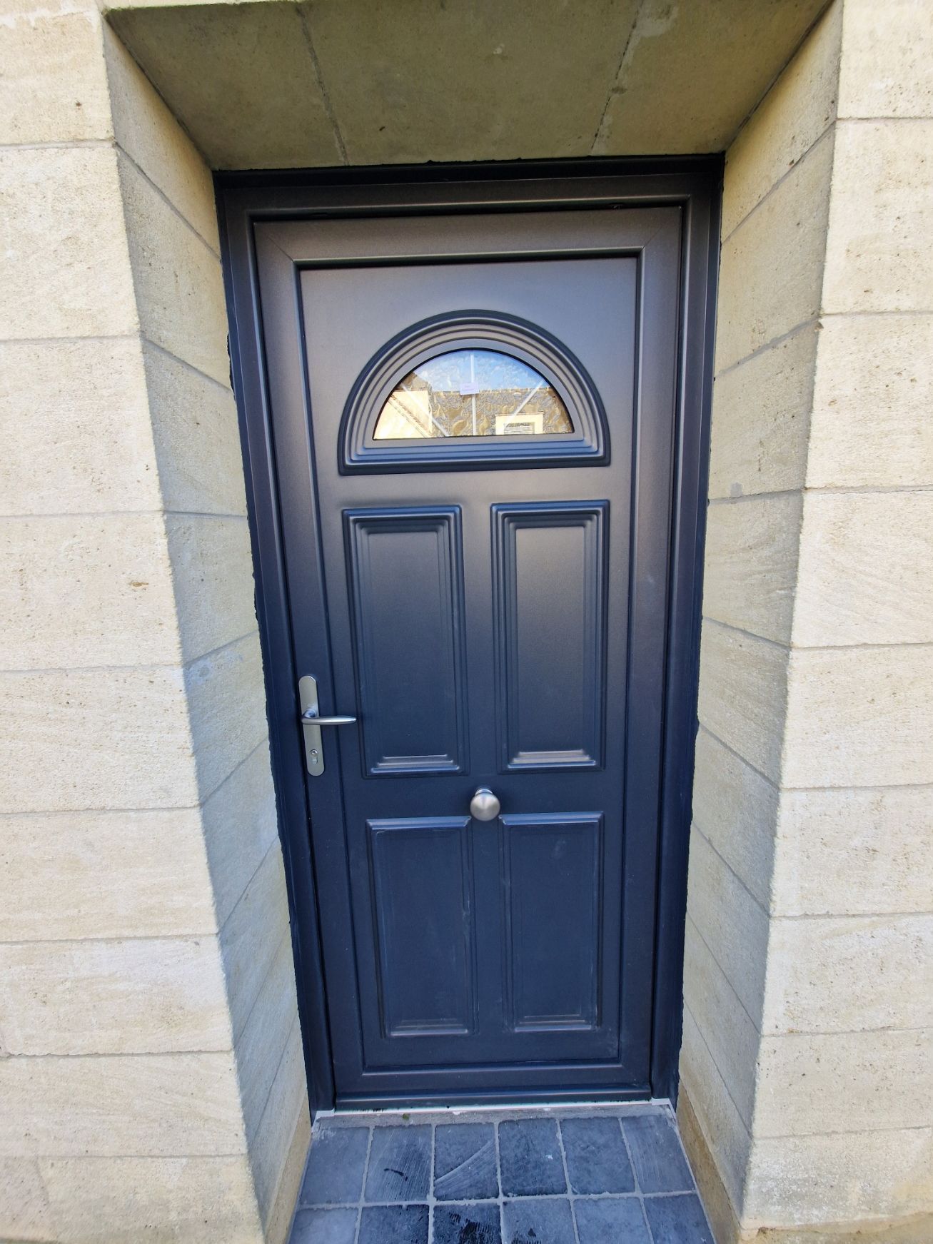 Un porte d'entrée avec un vitre en arc de cercle sur le haut