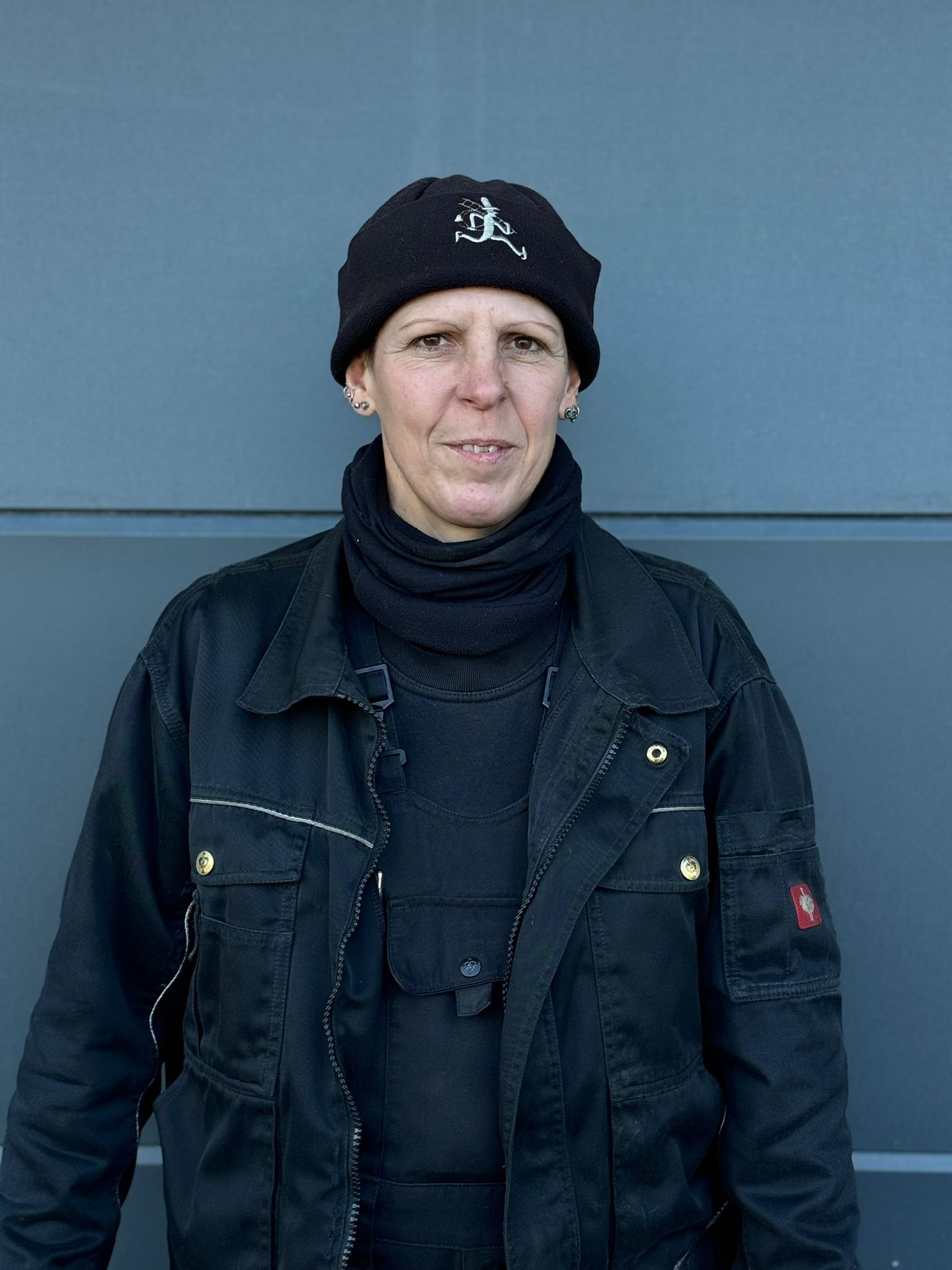 Ein Schornsteinfeger steht auf einem Dach und reinigt einen Schornstein.