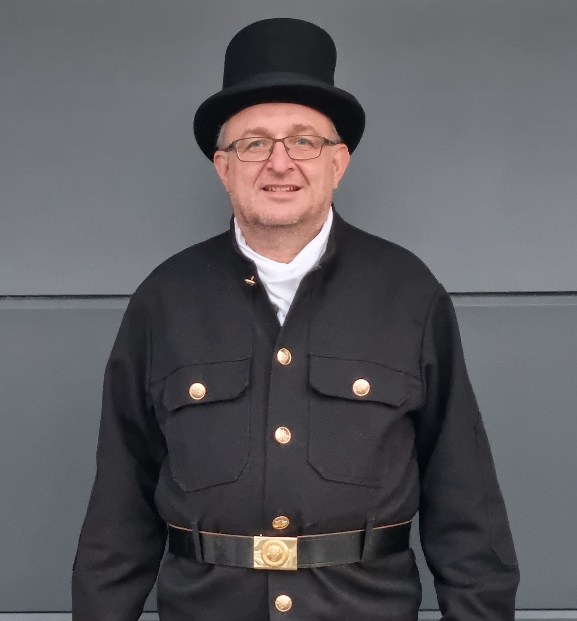 Ein Schornsteinfeger steht auf einem Dach und reinigt einen Schornstein.